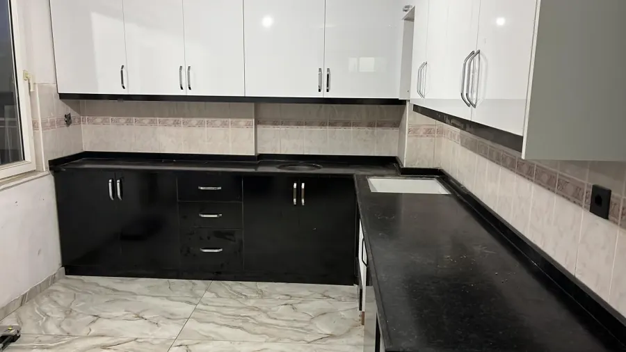 Beyaz dolaplı siyah tezgahlı köşe mutfak